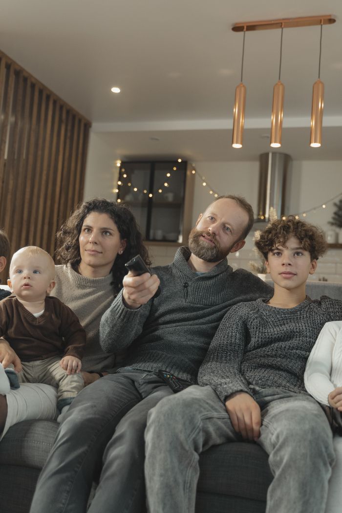 A family sitting together on a sofa in a living room, enjoying a cozy atmosphere.