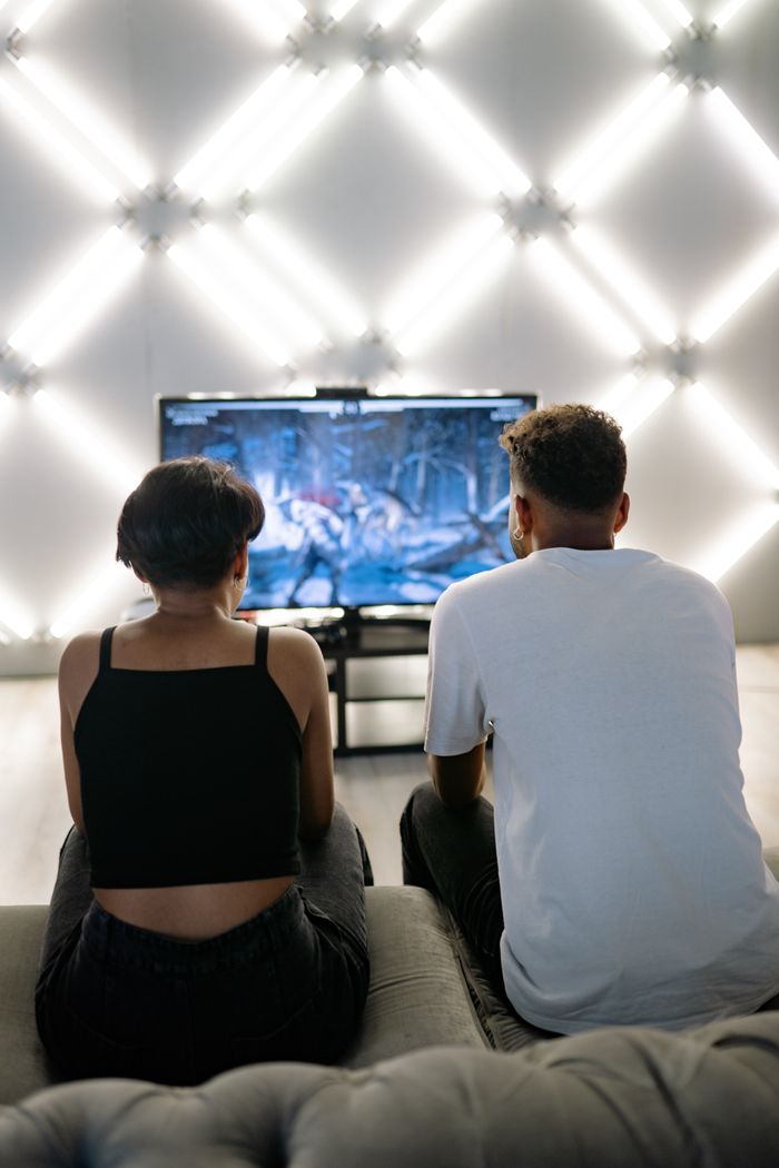 Two people sitting on a couch playing a video game together indoors.
